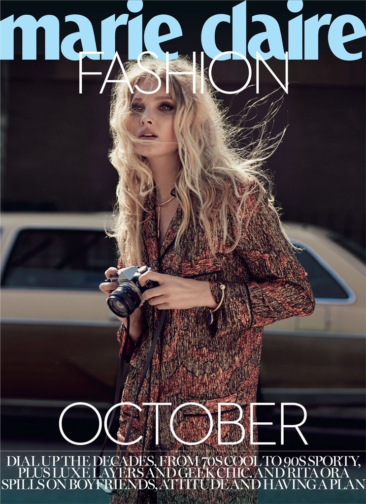 The model poses with a camera in hand while wearing a boho chic look