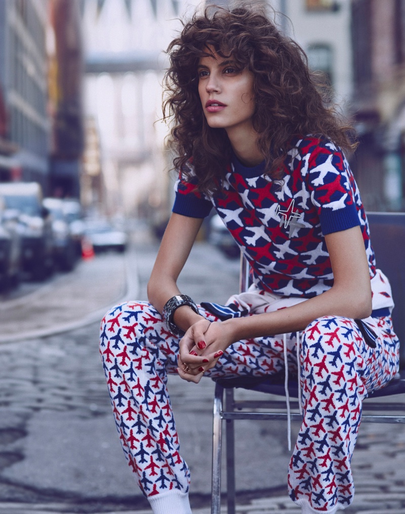 Sitting down, Antonina models a Chanel sweater and trousers with a plane print