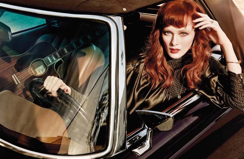 Posing behind the wheel of a car, Karen Elson models a black blouse with puffy sleeves