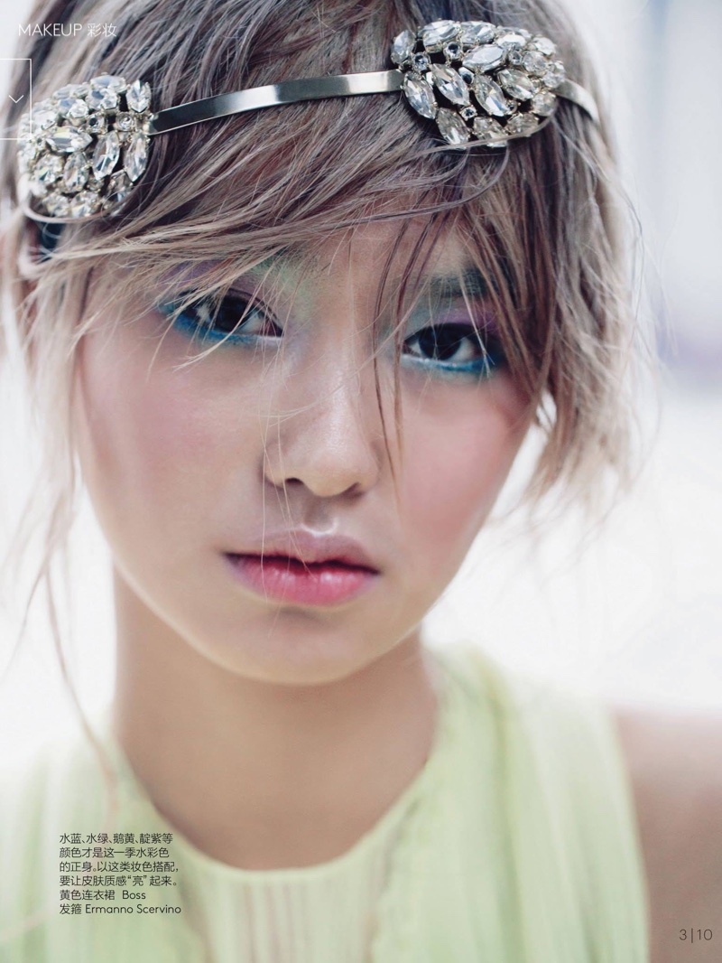 Wearing a crystal embellished headband, Estelle wears pastel colored eyeshadow with pink-blush on her cheeks