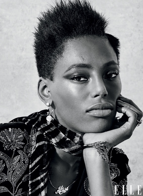 Model wears short natural hairstyle with trimmed sides