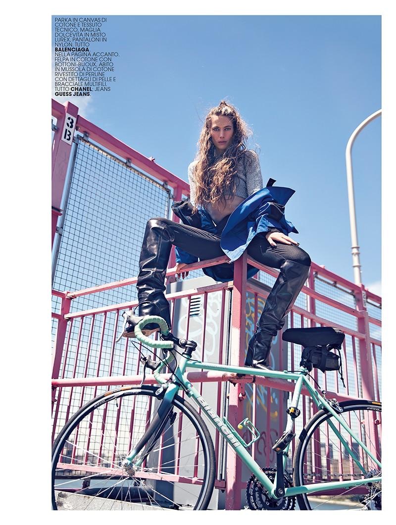 Posing on a bike, Jessica Miller wears parka, cropped sweater and pants from Balenciaga