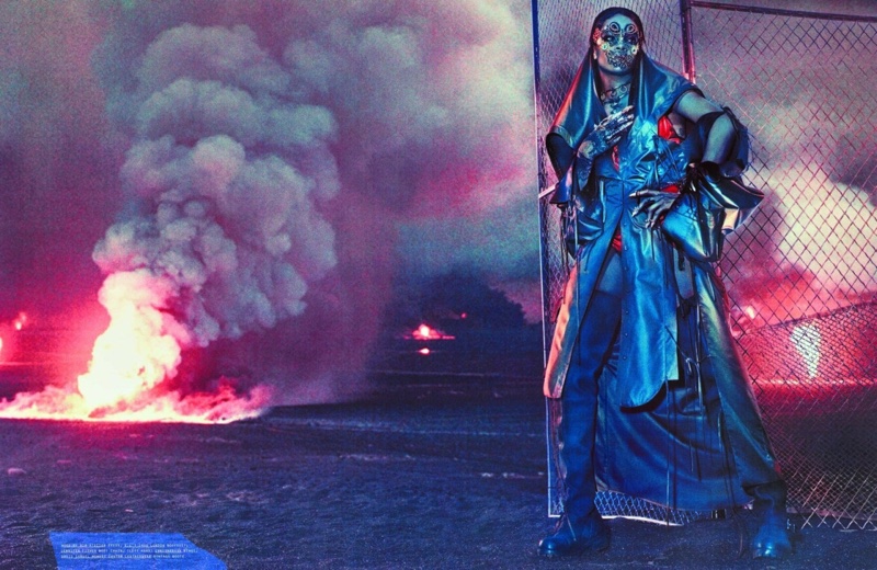 Rihanna poses next to a chainlink fence wearing Hood by Air Atelier dress, E.L.F. Zhou London Bodysuit and Jennifer Fisher body chain