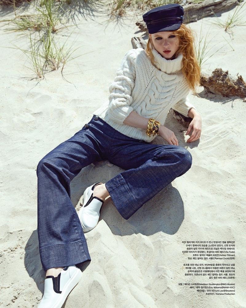 Laying on the sand, Madison Stubbington wears Gigi Hadid x Tommy Hilfiger cable knit sweater and flared denim