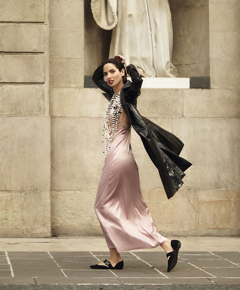 Walking down the street, the model wears a black jacket with a pink slip dress