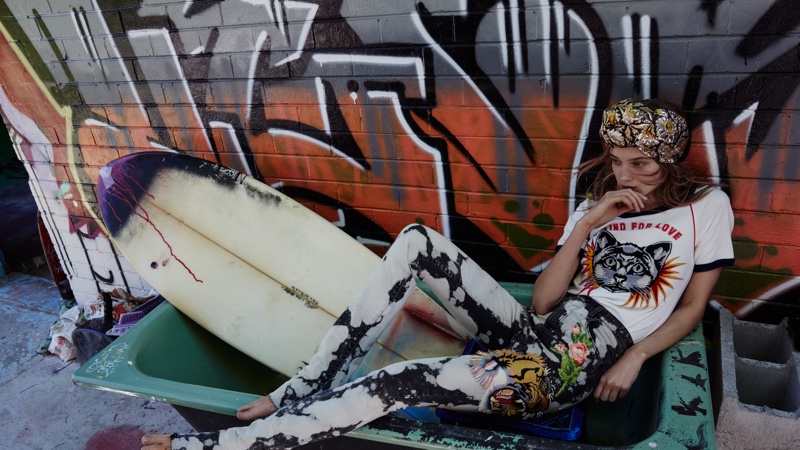 Posing next to a graffitied wall, Rosie Tupper models Gucci shirt, denim pants and headband