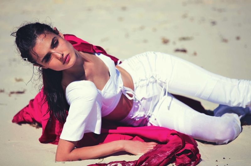 Posing on the sand, Blanca Padilla models Haider Ackermann trench coat with Diesel Black Gold crop top and jeans