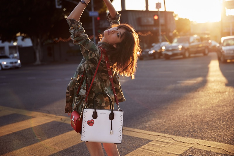 Model Hikari Mori poses in Michael Kors Scout crossbody bag with two-toned Mercer bag
