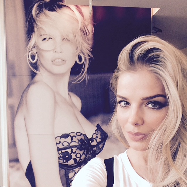 Danielle Knudson poses with old Guess photo of Claudia Schiffer