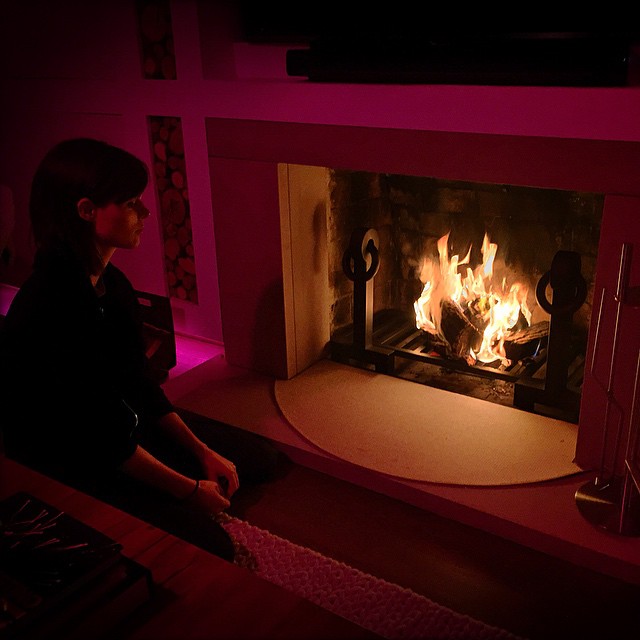 Coco Rocha sits near a fireplace
