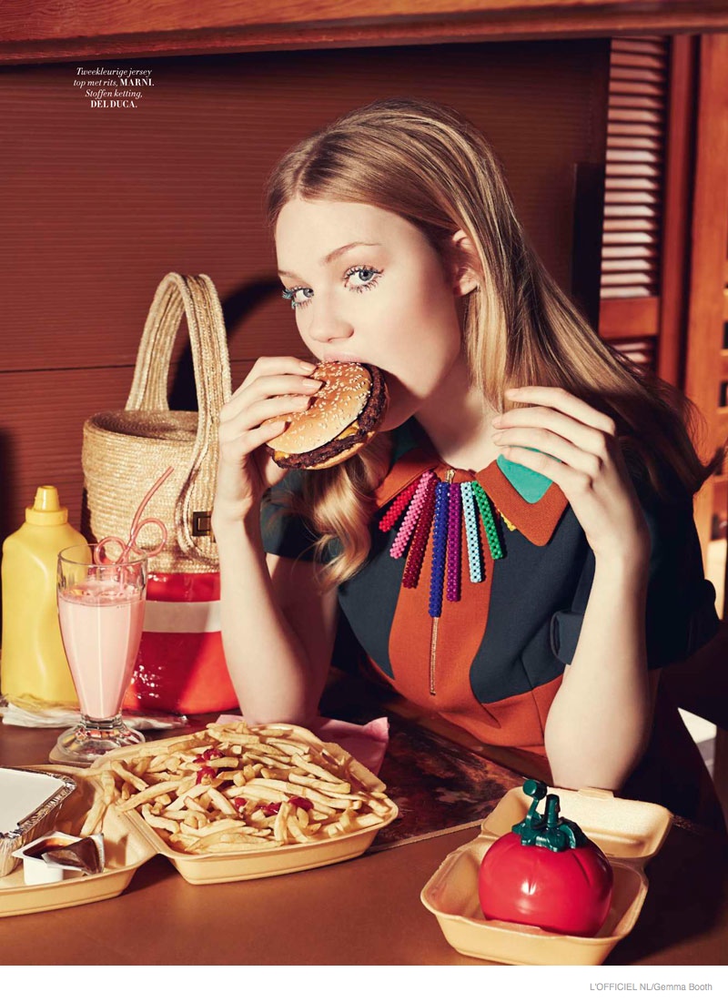 Zanna eats a hamburger while modeling colorful Marni dress and Del Duca necklace. 
