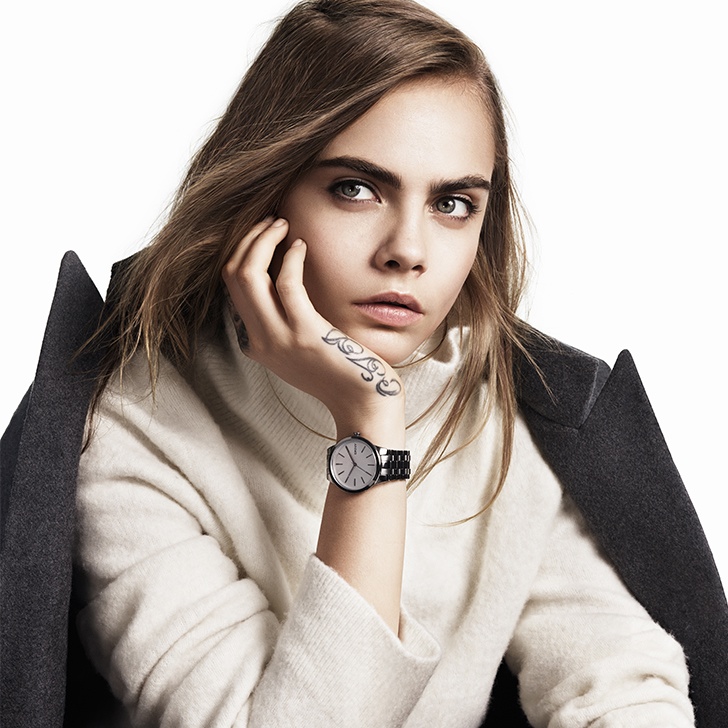Cara wears a light knit with a coat draped over her shoulders