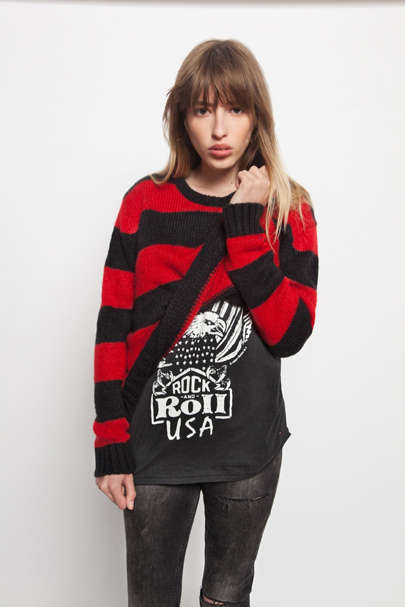 A model wears a striped sweater paired with a rock and roll tee