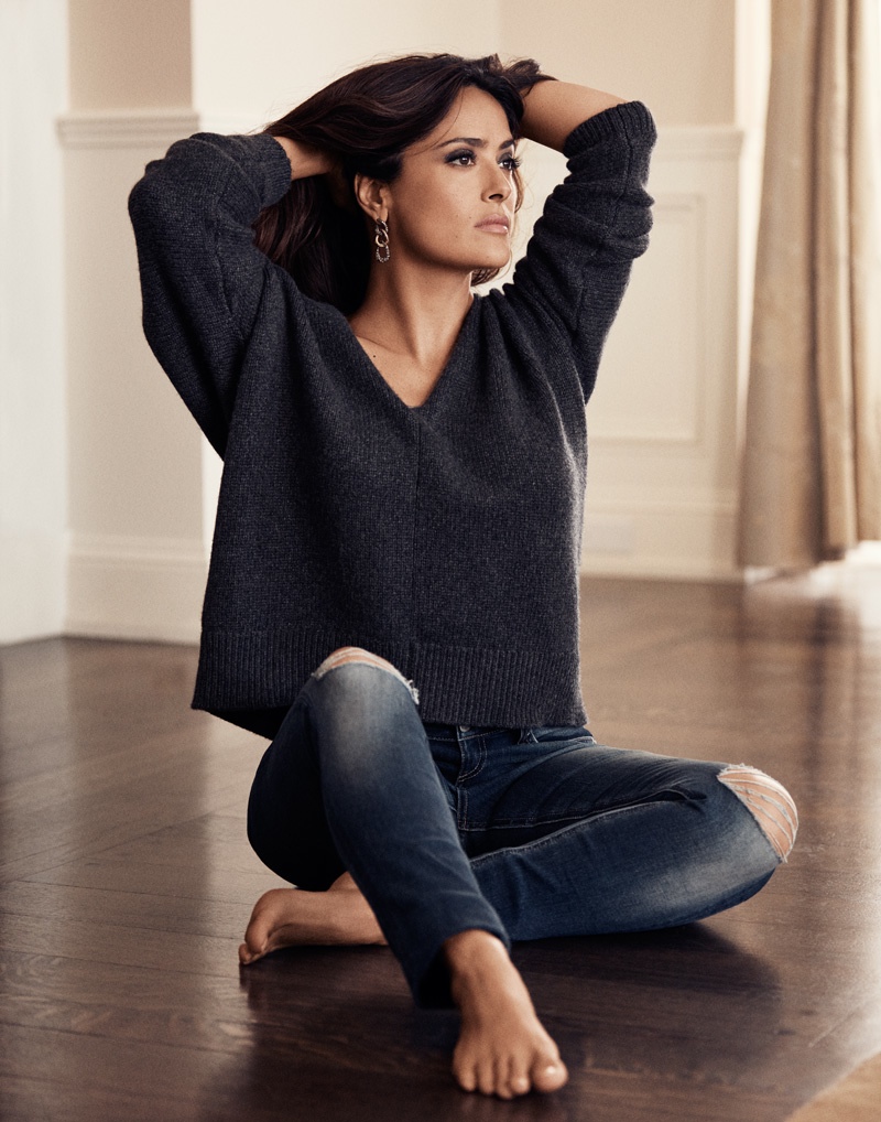 Salma wears a pullover sweater and ripped denim