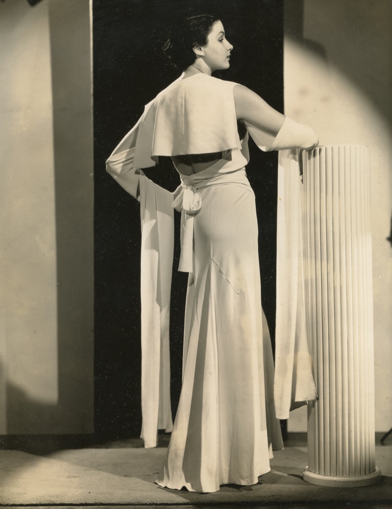 Back view of a white crepe evening gown with low back décolleté, back sailor collar, floating arm panels. Photo by unknown (United States). Circa 1931. Timeline Archive. 