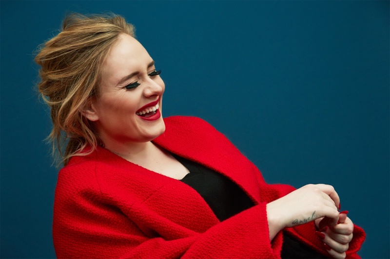The singer is all smiles in a red cardigan jacket