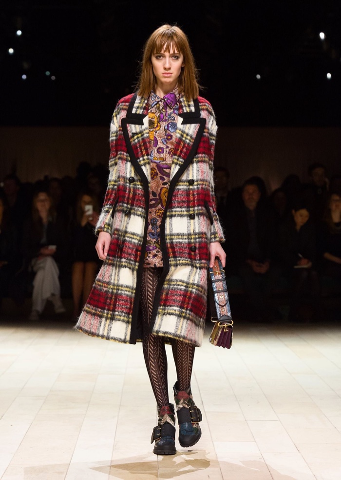 Model walks the runway at Burberry’s fall-winter 2016 show wearing a plaid coat and pink floral jacquard dress