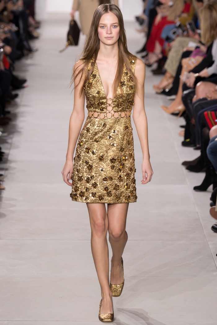 A model walks the runway in a gold shift dress from Michael Kors' fall-winter 2016 collection
