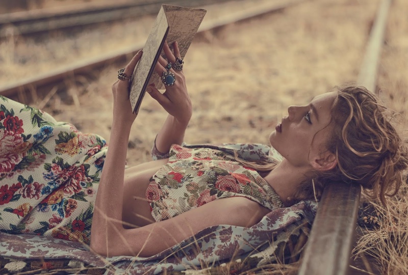 The model lounges in a floral crop top and skirt as she reads a book