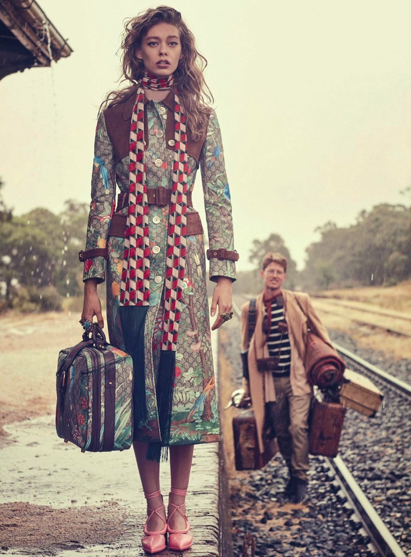 Posing with a bag of luggage, Ondria models a colorful trench from Gucci by Alessandro Michele with checkered scarf