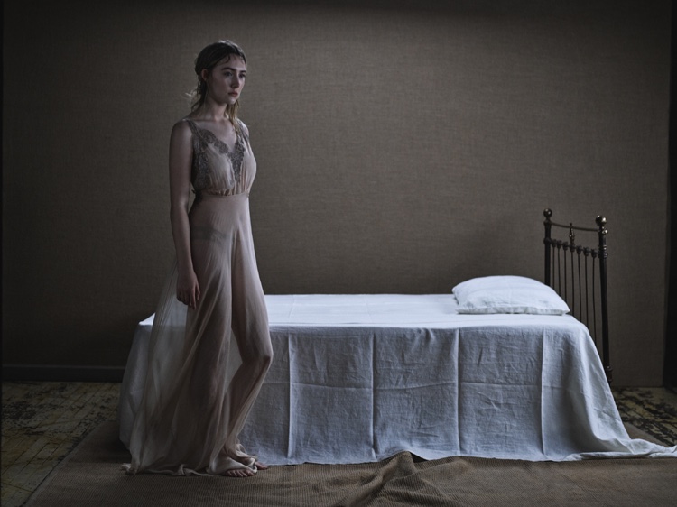 Photographed next to a bed, Saoirse Ronan wears a sheer Rosamosario dress