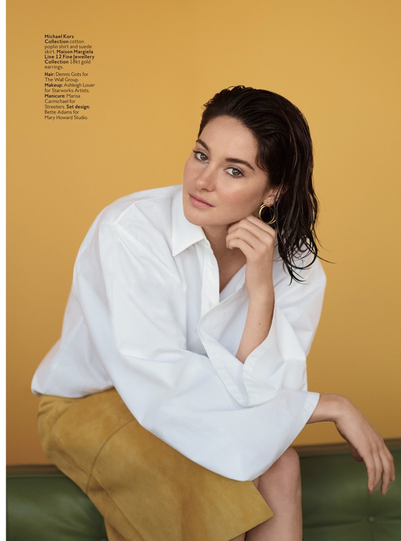 Shailene sits in a casual look from Michael Kors Collection with a white shirt and brown suede skirt