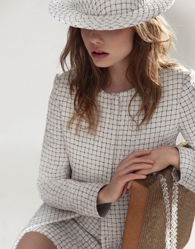 Kristine Froseth models a printed boater hat with a black and white tweed jacket and skirt from Chanel
