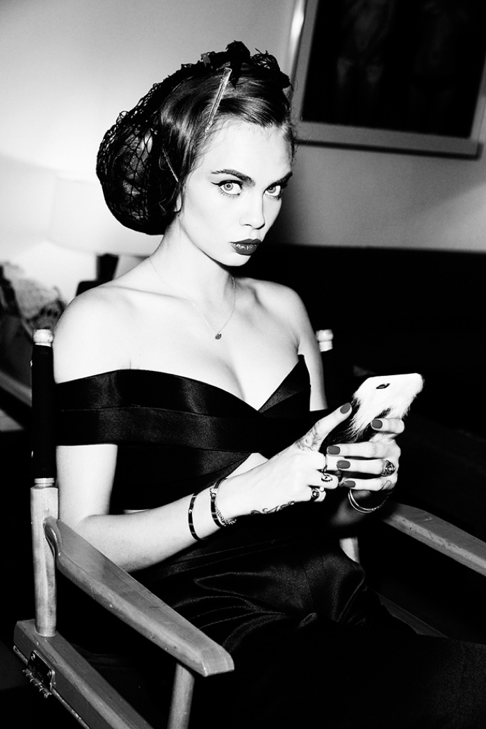 Captured in black and white, Cara Delevingne takes a moment to glance away from her cell phone