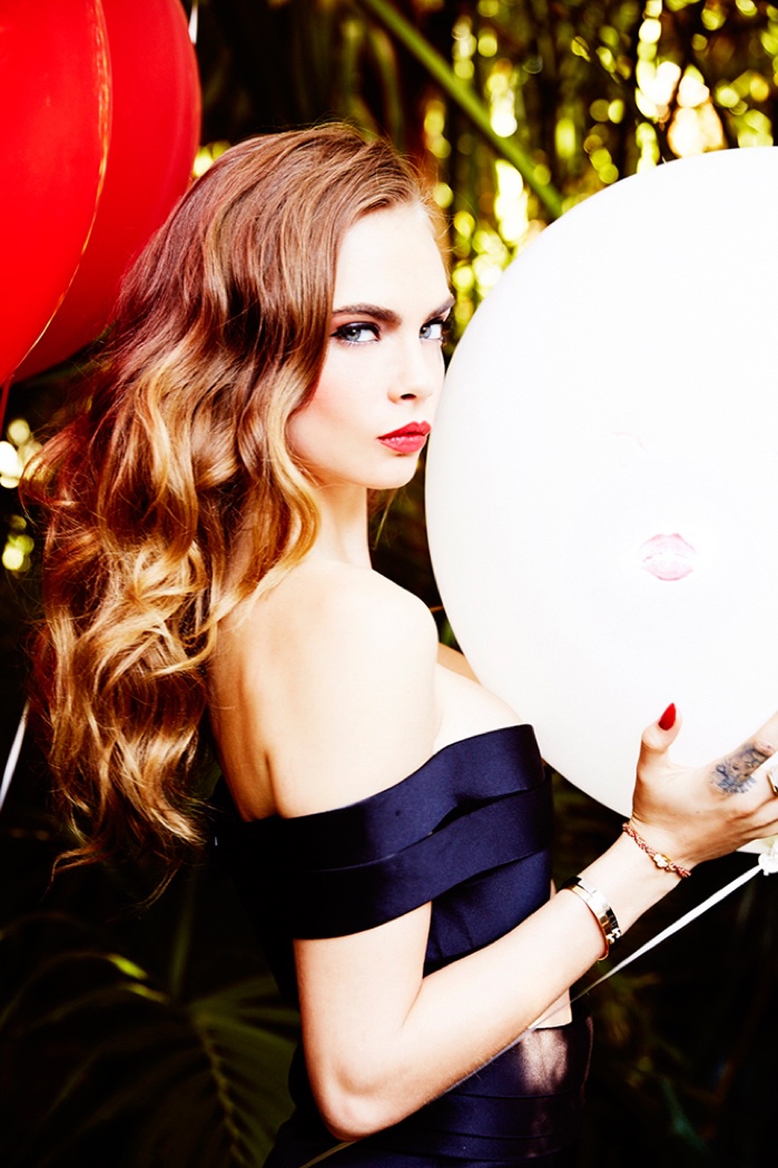 Captured with balloons, Cara Delevingne models her hair in blonde waves with a pop of red lip color