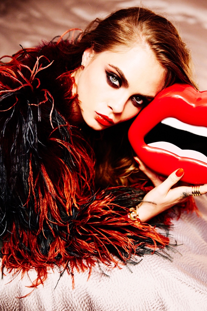 Rocking a fur coat and mouth-shaped bag, Cara Delevingne models smokey eyeshadow and siren-red lipstick