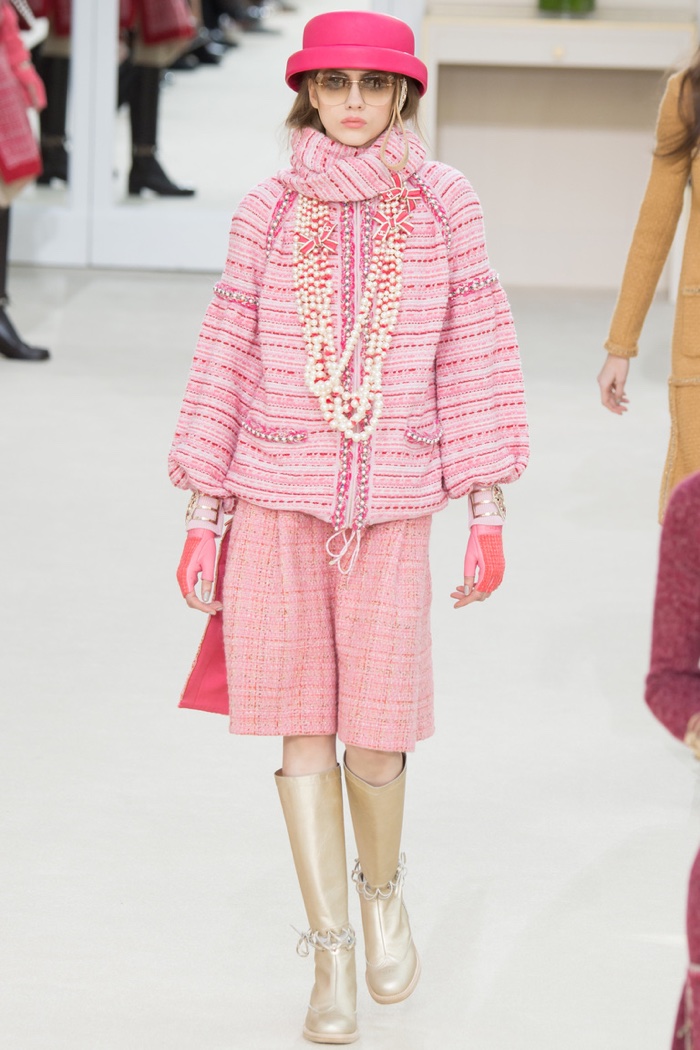 A model walks the runway at Chanel's fall-winter 2016 show wearing a pink tweed jacket and skirt with gold boots