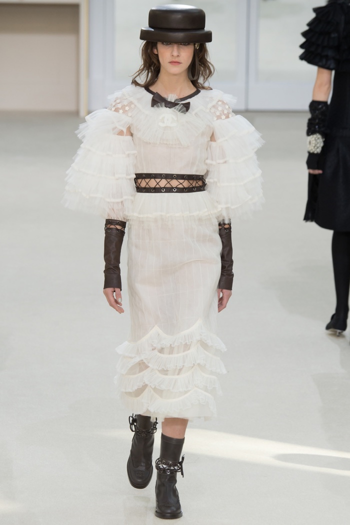 Mica A walks the runway at Chanel's fall-winter 2016 show wearing a white dress with ruffles and a boater hat