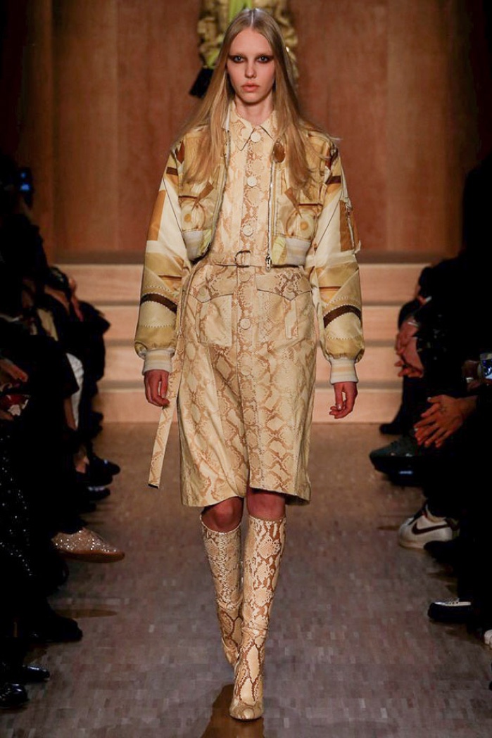 A model walks the runway at Givenchy's fall-winter 2016 show wearing a cropped bomber jacket, python print dress and knee-high boots