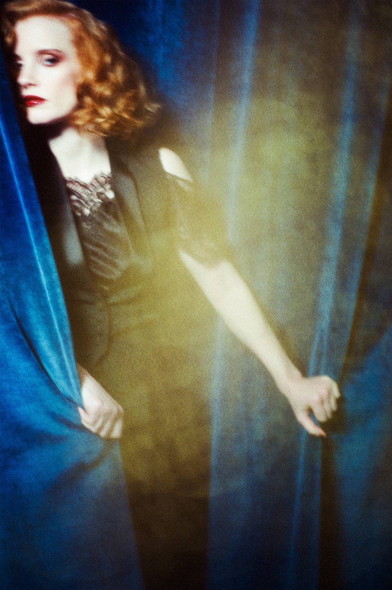 Jessica Chastain hides behind a curtain while wearing Givenchy jacket, lace top and black trousers