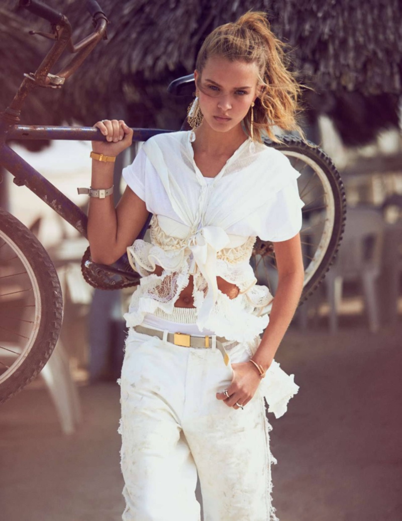 Holding a bike, Josephine wears a Balenciaga top with distressed white pants