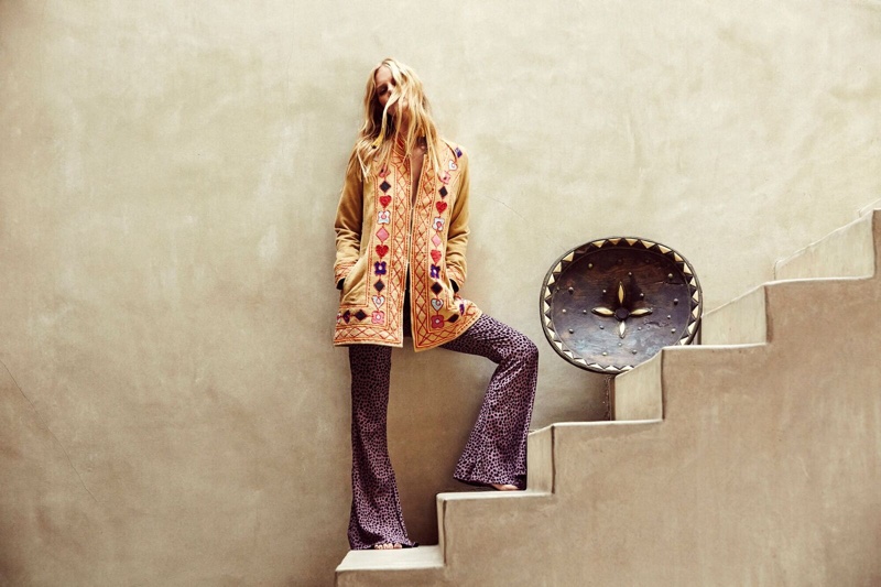 Marloes Horst poses on stairs while modeling an embroidered jacket and flared pants