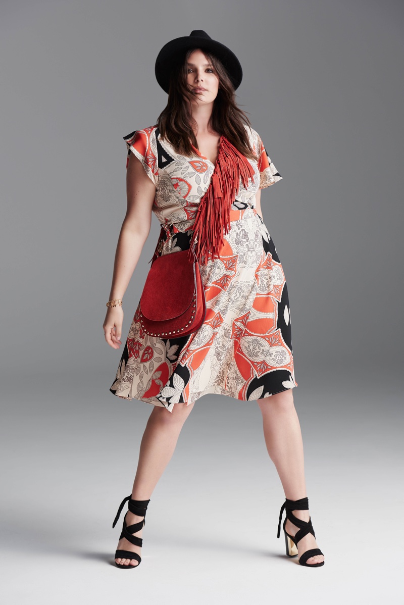 Wearing a wide-brimmed hat and printed mid-length dress, Candice Huffine models for River Island's plus size collection