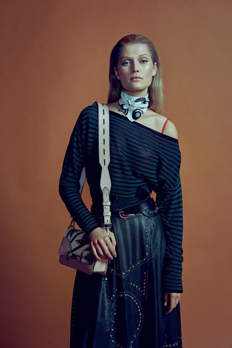 Photographed in the studio, Toni Garrn models an off the shoulder sweater, high-waist trousers and saddle bag from Tod's