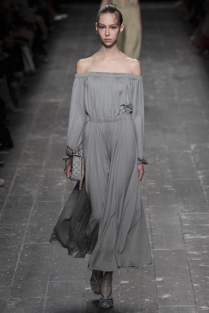 A model walks the runway at Valentino's fall-winter 2016 show wearing an off the shoulder long-sleeve gown