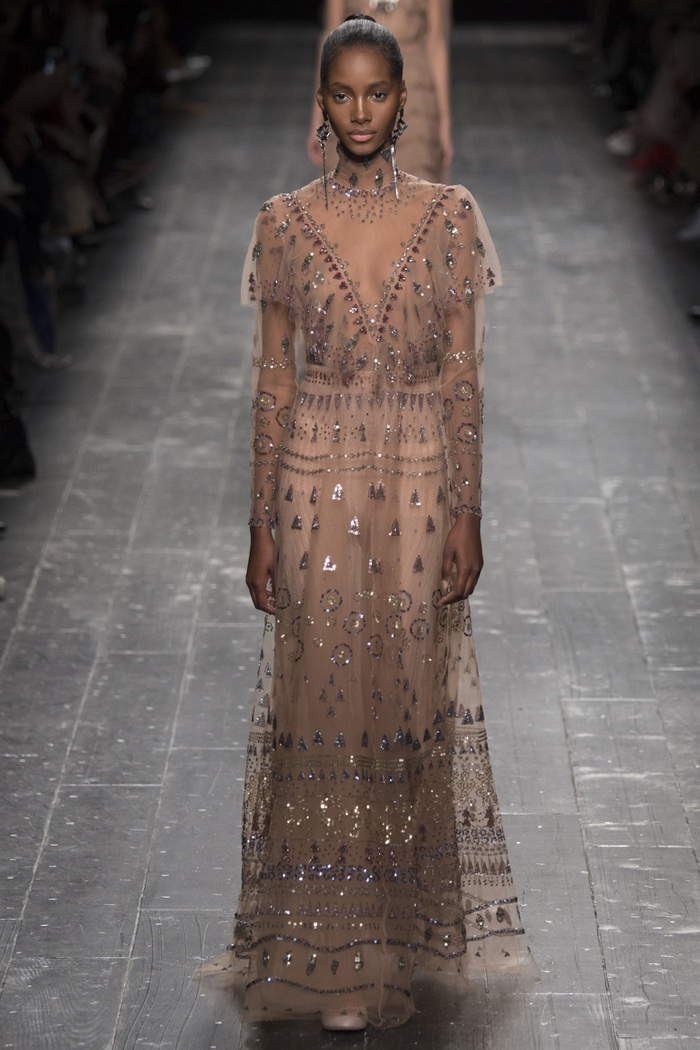 A model walks the runway at Valentino's fall-winter 2016 show wearing a sheer gown with crystal embellishments