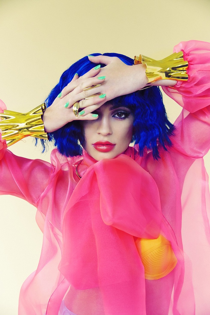 Wearing a blue wig, Kylie Jenner models a pink blouse and red lipstick color