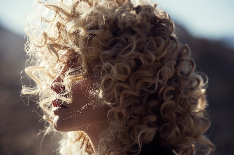 The blonde model wears a curly hairstyle