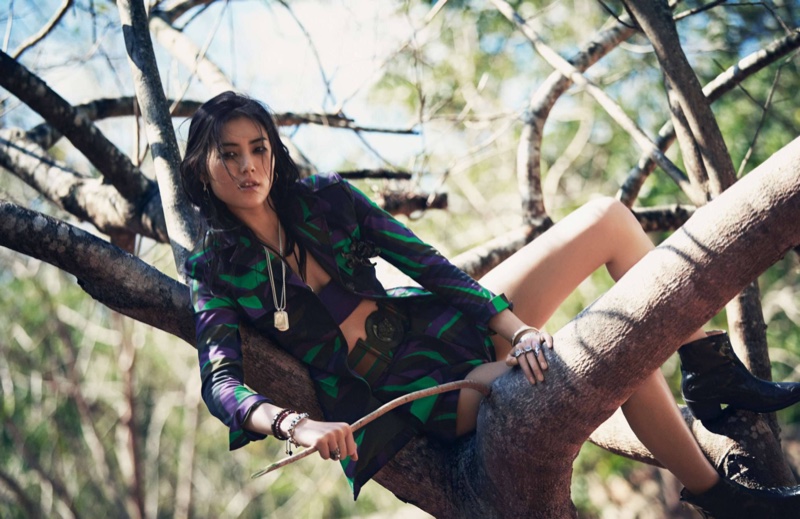 Liu Wen poses in a tree wearing a Versace jacket and skirt with matching prints
