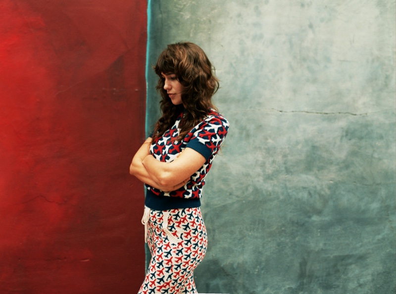 With her arms crossed, Lola Kirke poses in a Chanel sweater and pants with airplane print