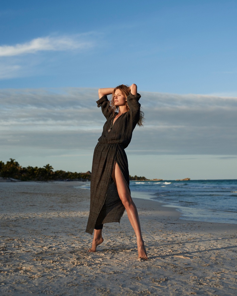 Constance Jablosnki poses barefoot in the sand wearing a Masscob maxi dress