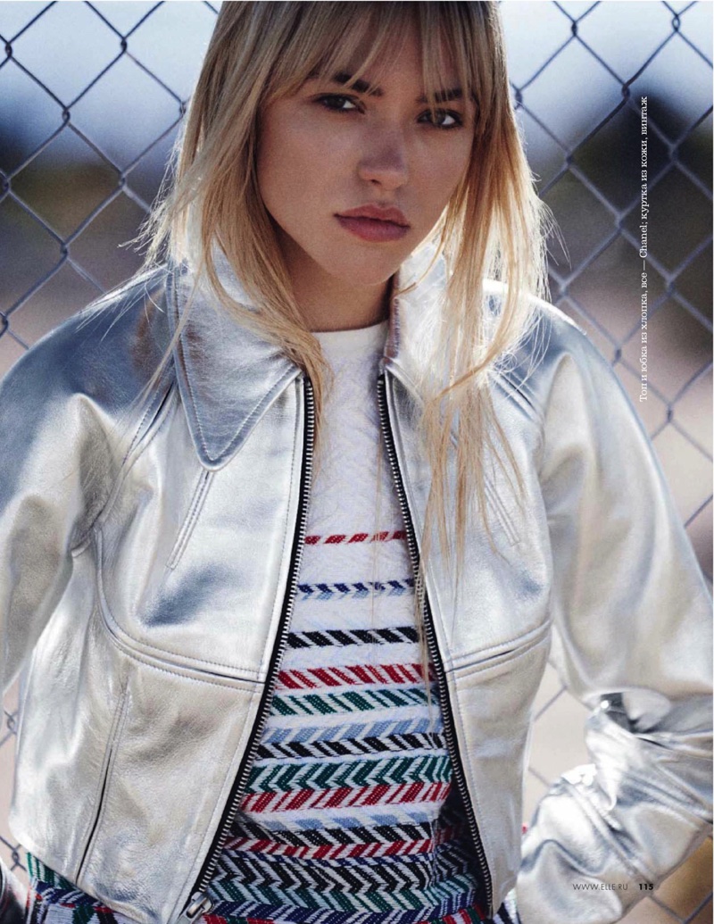 The blonde poses in silver bomber jacket and knit top