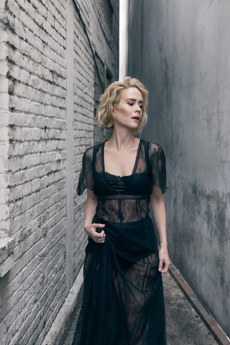 Sarah Paulson wears a black sheer lace dress with bra and underwear