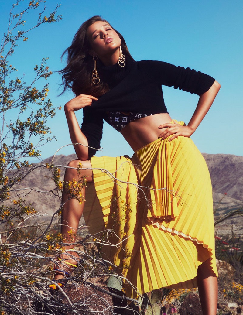 Anais Pouliot wears cropped sweater with printed bikini top and yellow pleated skirt