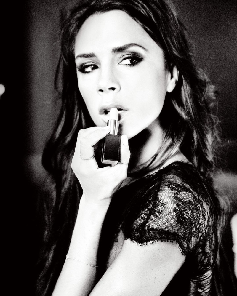Photographed in black and white, Victoria Beckham poses with lipstick 