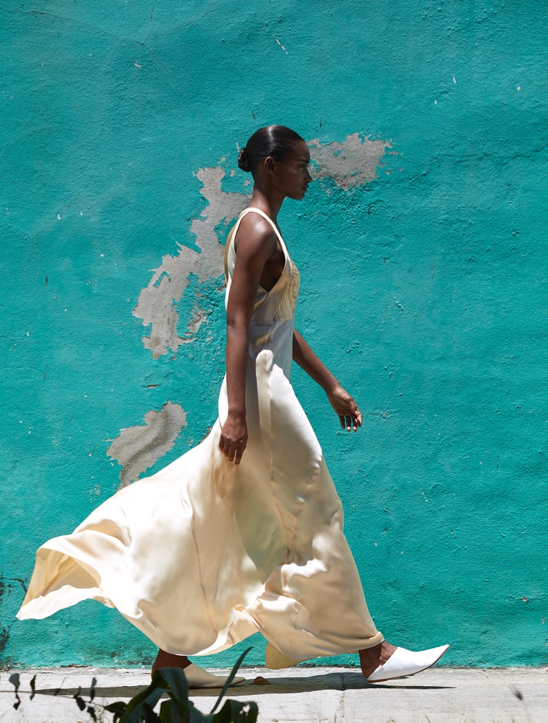 The model walks the streets in a silk dress with pointed heels